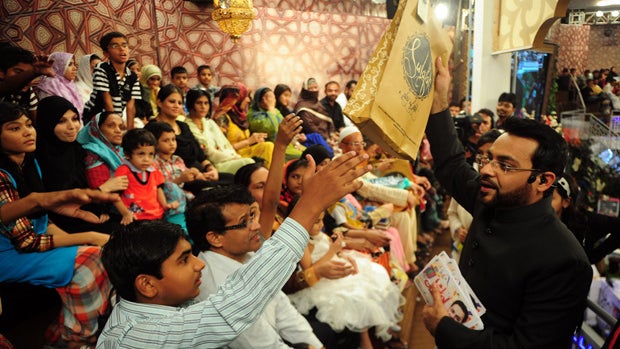 Pakistani television show host Aamir Liaquat Hussain (R) distributing gifts to audience during an Islamic quiz show last month 