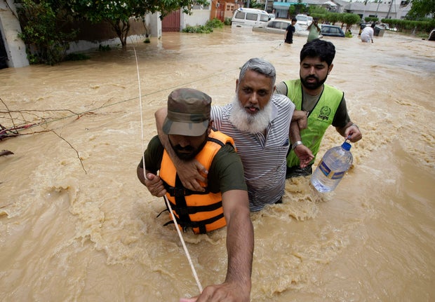 Pakistani soldiers rescue a resident from an area flooded by heavy rains on the outskirts of Karachi, Pakistan