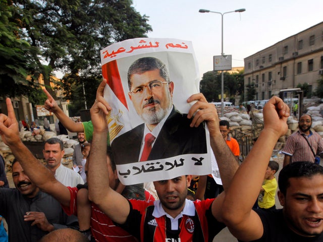 Supporters of Egypt's ousted President Mohammed Morsi walk through makeshift barriers to a sit-in at Nahda Square, which is fortified with multiple walls of bricks, tires, metal barricades and sandbags, where protesters have installed their camp near Cairo University in Giza, southwest of Cairo, Egypt, Saturday, Aug. 10, 2013.