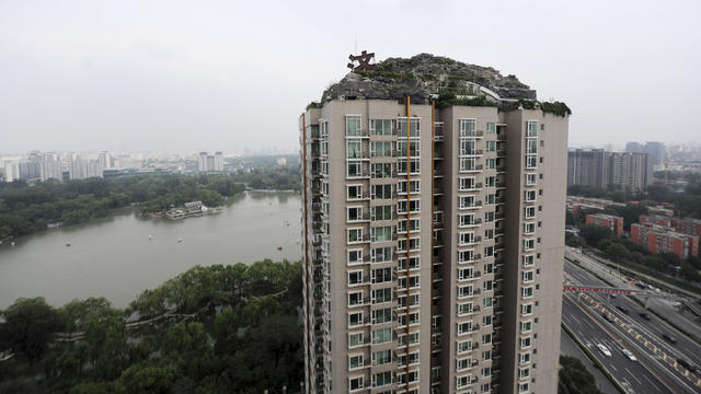 A residential building with a rocky style villa on its roof 