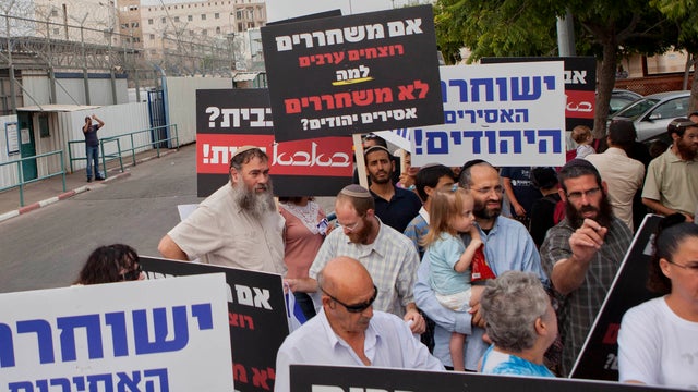 Israelis hold signs outside the Ayalon prison as they demand the release of the Israelis convicted for killing Palestinians, near the town of Ramle, Israel, Aug. 13, 2013.  