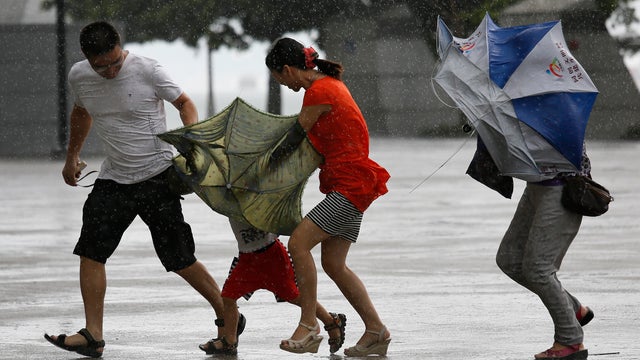 A family battles strong wind and rain as Typhoon Utor hits Hong Kong Aug. 14, 2013.  