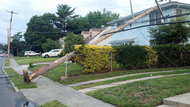 Toppled utility pole falls against a house in Elmont, N.Y. 