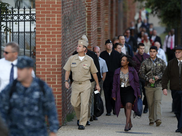 Military personnel and workers walk along the perimeter of the Washington Navy Yard Sept. 19, 2013. 
