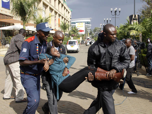A security officer helps a wounded woman outside the Westgate Mall in Nairobi, Kenya, Sept. 21, 2013, after gunmen threw grenades and opened fire during an attack that left multiple people dead and dozens wounded. 