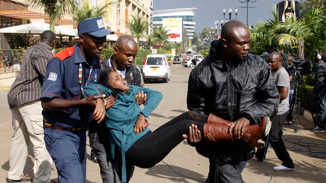 A security officer helps a wounded woman outside the Westgate Mall in Nairobi, Kenya, Sept. 21, 2013, after gunmen threw grenades and opened fire during an attack that left multiple people dead and dozens wounded. 