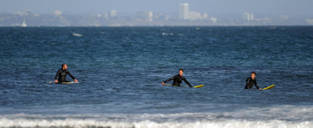 Three surfers wait to catch the swell at 610 header 