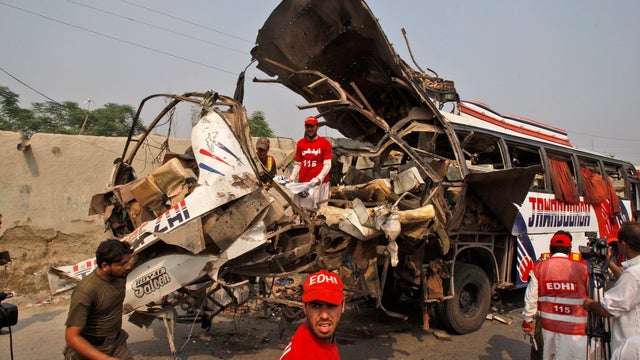 Pakistani rescue workers check the wreckageof a bus carrying government employees which was destroyed 