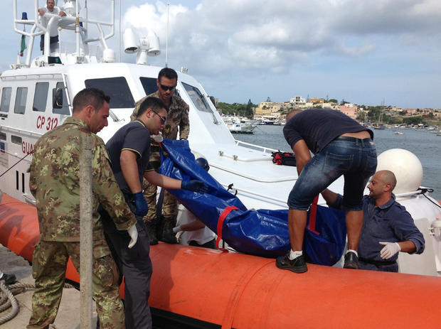 The body of a drowned migrant is unloaded from a Coast Guard boat in the port of Lampedusa 