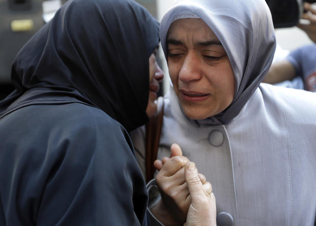 A Syrian refugee woman, left, cries as she says goodbye to her relative who is waiting to board a bus to Beirut International Airport for a flight to Germany 
