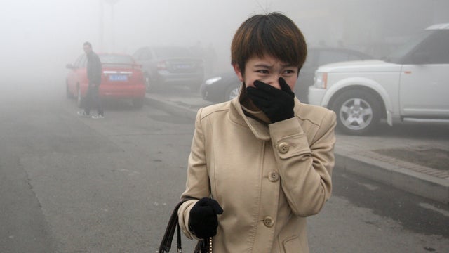 A woman walks along a road in Harbin, China, as heavy fog engulfs the city. 