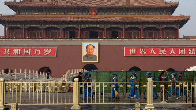 Cleaners walk past area shielded by green nets in front of Tiananmen Gate following car crash/fire on Oct. 28, 2013 