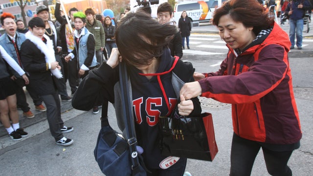 A South Korean student and mother run toward a gate for the Scholastic Aptitude Test, in front of an examination hall in Seoul 