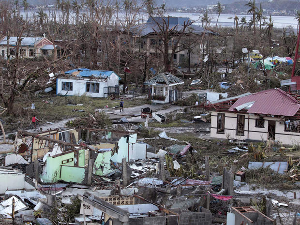 A resident walks by remains of houses after powerful Typhoon Haiyan slammed into Tacloban on hardest-hit Leyte Island in the Philippines Nov. 9, 2013. 