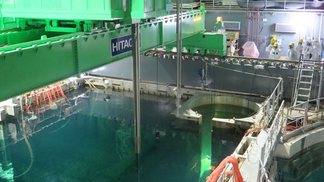 Workers remove nuclear fuel rods from a pool at No. 4 reactor of the Fukushima Daiichi Nuclear Power Plant 