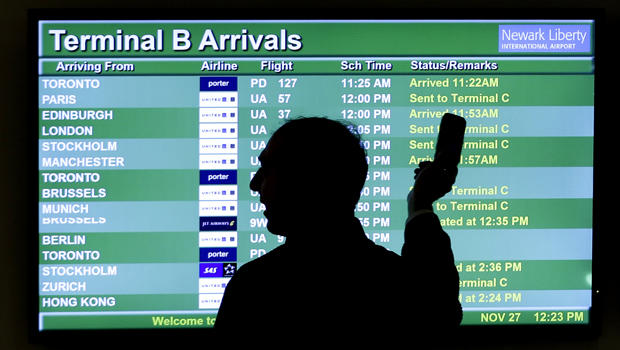 A person points to a screen displaying an airplane travel list while he talks on a phone at Newark Liberty International Airport as travelers get a head start on Thanksgiving Day travel Nov. 27, 2013, in Newark, N.J. 