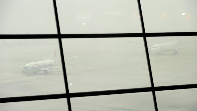 Airplanes queue to take off while shrouded in smog at Beijing International Airport  