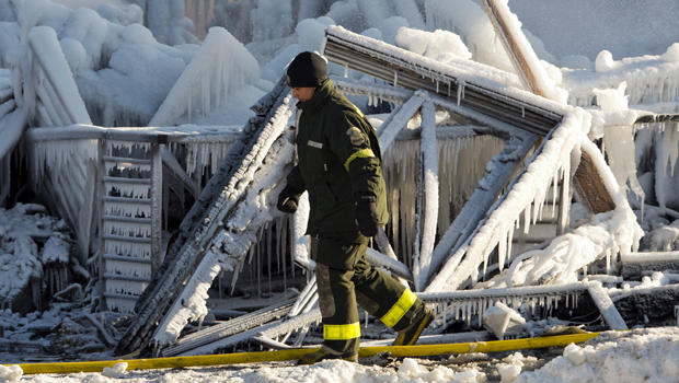 A police investigator looks over the frozen rubble after a fire destroyed a seniors residence in L'Isle-Verte, Quebec, Jan. 23, 2014. 