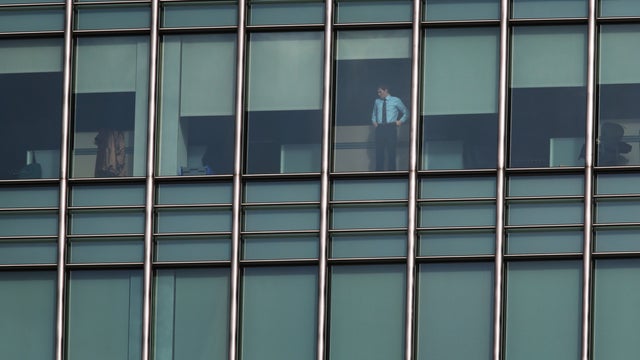 A person looks out of the window of the JP Morgan building at Canary Wharf, in London's financial district 