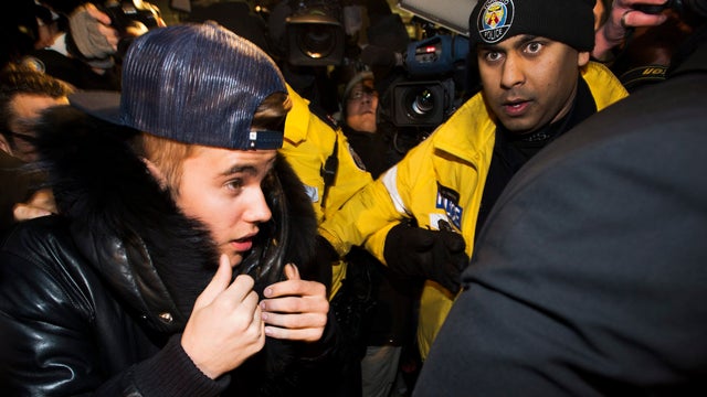 Justin Bieber is swarmed by media and police officers as he turns himself in to city police for an expected assault charge, in Toronto, on Wednesday, Jan. 29, 2014 