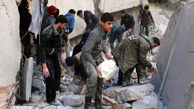 Syrians inspect the rubble of destroyed buildings following a Syrian government airstrike in Aleppo 