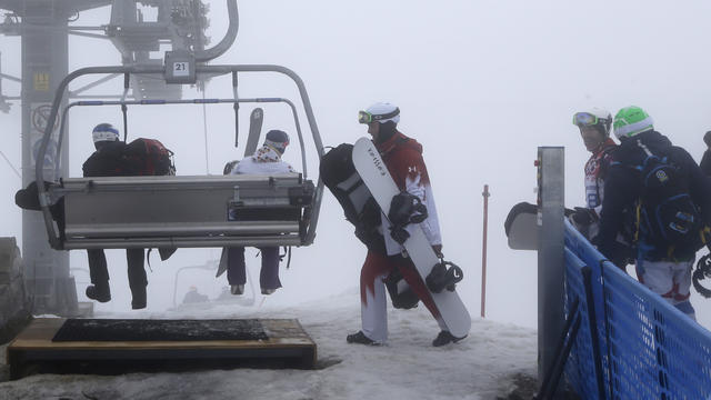 Canada's Robert Fagan, center, waits for a chairlift gondola after the men's snowboard cross competition was cancelled due to fog at the Rosa Khutor Extreme Park 