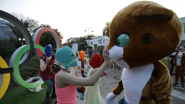 Pussy Riot member Nadezhda Tolokonnikova in the aqua balaclava, left, interacts with a person dressed as one of the Olympic mascots while the group performs next to the Olympic rings in Sochi, Russia, Feb. 19, 2014. 