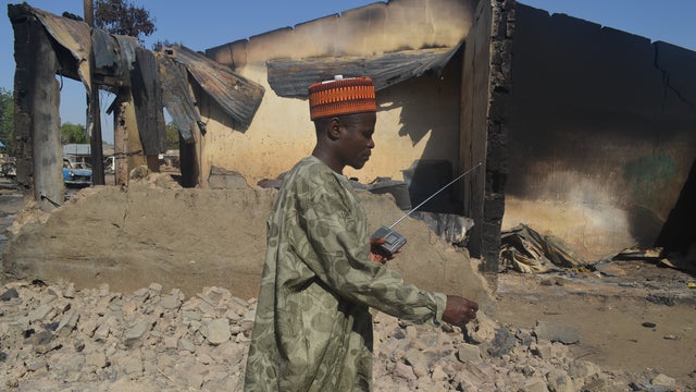 A man walks past a burnt out building following an attacked by Boko Haram in Bama, Nigeria 