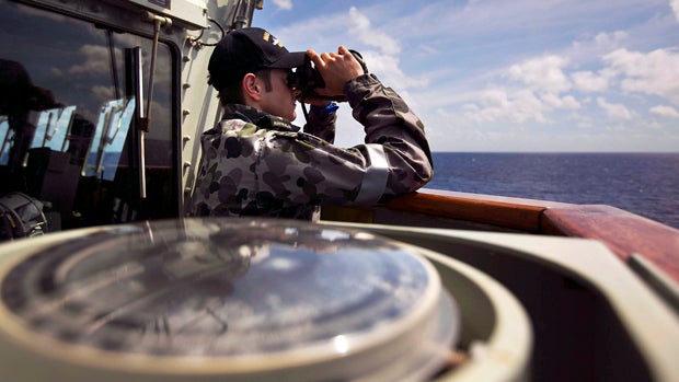 Able Seaman Boatswains Mate Marc Chandler looks through a pair of binoculars aboard the Australian Navy ship HMAS Success as it continues to search for missing Malaysian Airlines Flight 370 in this picture released by the Australian Defense Force April 11 