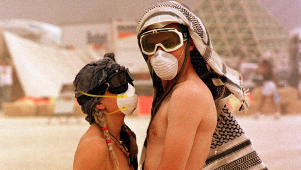 A couple wearing face masks embrace during a dust 