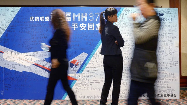 People walk past a billboard in support of missing Malaysia Airlines flight 370 as Chinese relatives of passengers on the flight attend a meeting at the Metro Park Hotel in Beijing 