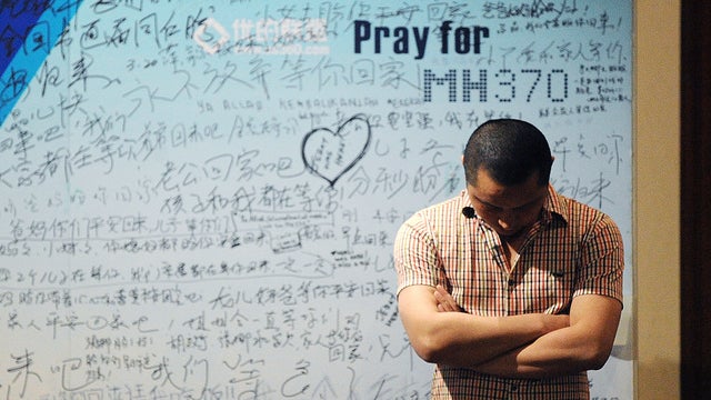 A man stands in front of a billboard in support of missing Malaysia Airlines flight MH370 as Chinese relatives of passengers on the missing Malaysia Airlines flight MH370 have a meeting at the Metro Park Hotel in Beijing 