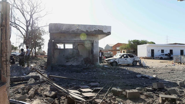 Military personnel stand near the damaged entrance to an army camp after a suicide bombing in Benghazi 