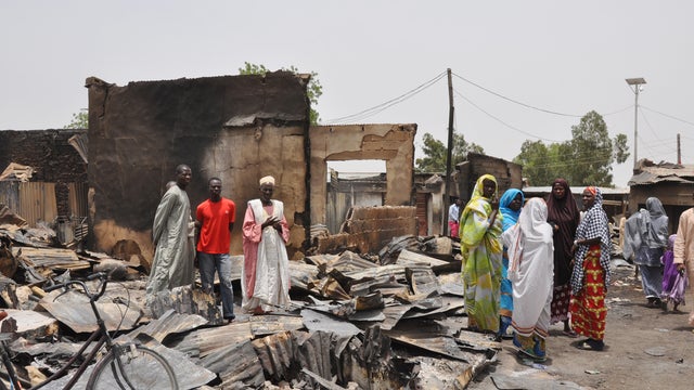 People stand outside burnt houses following an attack by Islamic militants in Gambaru, Nigeria 