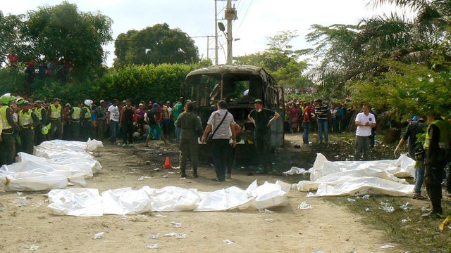 Colombian policemen stand alongside recovered bodies of children who died in a burned bus in Fundacion, northern Colombia 