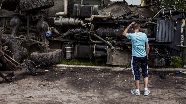 A Ukrainian man stands in front of a truck previously used by pro-Russian militants before being destroyed in bombing by the Ukrainian military in Donetsk 