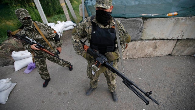 Pro-Russian armed men, wearing black and orange ribbons of St. George, a symbol widely associated with pro-Russian protests in Ukraine, stand guard at a checkpoint in Slavyansk 
