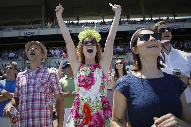 Shayna Reade, center, cheers as horses cross the finish line during the third race at Belmont Park before the 2014 Belmont Stakes in Elmont, New York, June 7, 2014. 