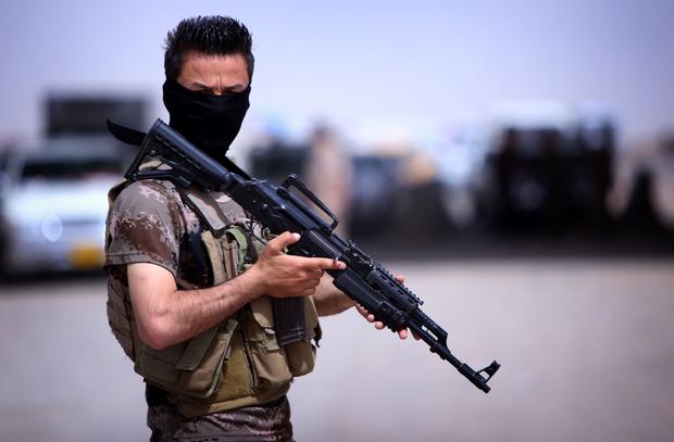 A masked Pershmerga fighter from Iraq's autonomous Kurdish region guards a temporary camp set up to shelter Iraqis fleeing violence in the northern Nineveh province on June 13, 2014. 
