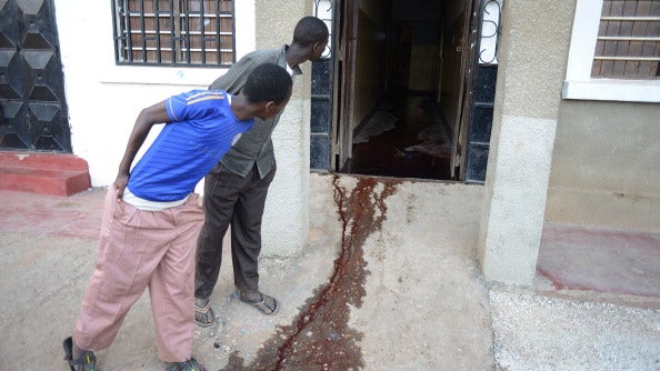 Men look at a pool of blood at the entrance of a restaurant where most of the people who ran to hide were shot in the town of Mpeketoni 
