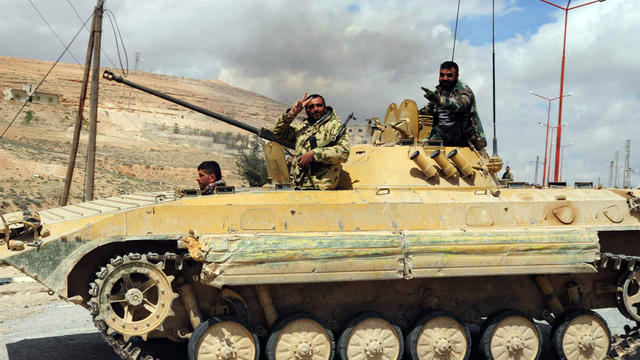 Syrian soldiers flash the sign for victory as they drive a tank in al-Sarkha village in the Qalamun mountains, northeast of Damascus, after taking control of the village from rebel fighters April 14, 2014. 