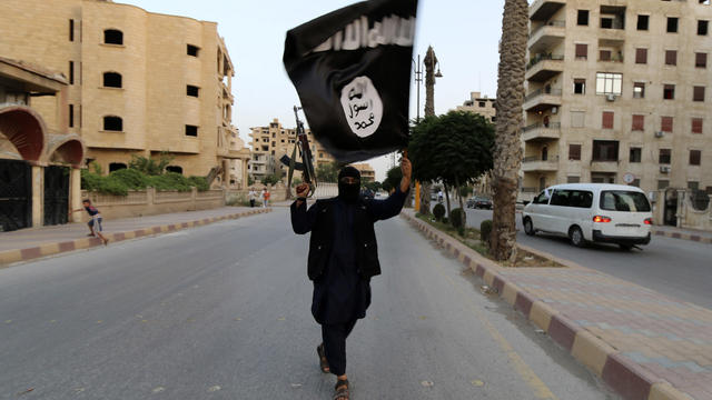 A member of the Islamic State in Iraq and Syria (ISIS) waves the group's flag in Raqqa, Syria 