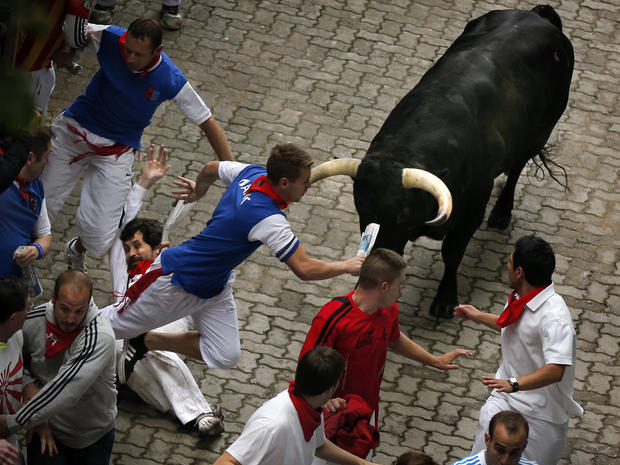 U.S. runner Bill Hillmann, 35, from Chicago, center left, falls seconds before a Victoriano del Rio ranch fighting bull gored him on his right leg during the running of the bulls at the San Fermin festival in Pamplona, Spain, July 9, 2014. 