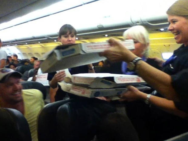 A Frontier Airlines flight attendant passes out pizza to passengers aboard a Denver-bound flight diverted to Cheyenne, Wyo., July 7, 2014. The airplane pilot treated his passengers to the pizza after they were diverted. 