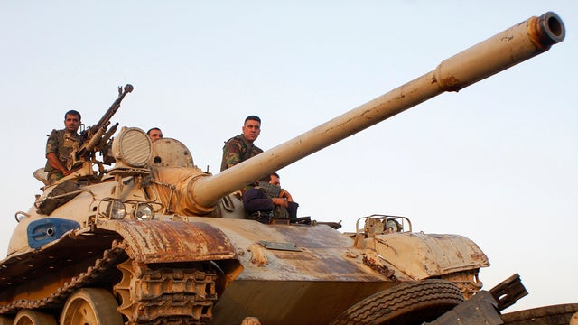 Kurdish "peshmerga" troops move down a street next to a transported tank during an intensive security deployment after clashes with militants of the Islamic State in Iraq and Syria, or ISIS, in Jalawla, Diyala province, July 4, 2014. 