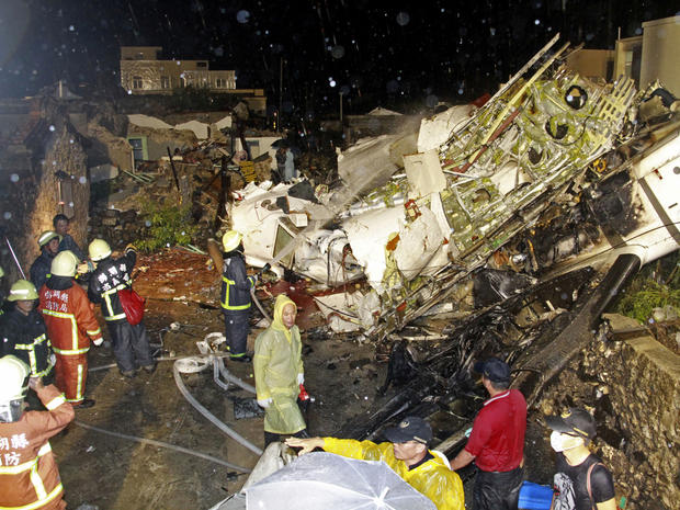 Rescue workers work next to the wreckage of TransAsia Airways Flight GE222, which crashed while attempting to land in stormy weather on the Taiwanese island of Penghu July 23, 2014. 