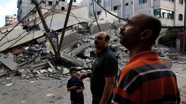 Palestinians gather beside a building that police said was hit by an overnight Israeli air strike in Gaza City July 25, 2014. 