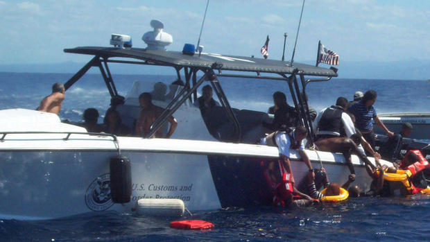 Office of Air & Marine agents pull migrants aboard their boat. 