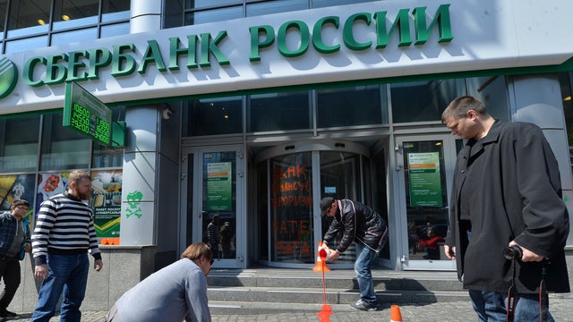 An activist paints symbolic blood from the flag of the so-called Donetsk Republic militia at the entrance of the Russian Sberbank office in Kiev, Ukraine, during a protest action April 18, 2014. 