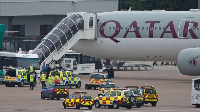 Passengers disembark from a Qatar Airways aircraft after a man was escorted off the plane by police at Manchester airport 